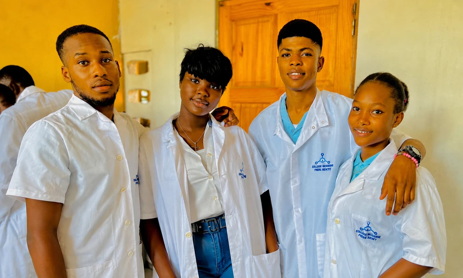 Quatre élèves du Collège Moderne Frère Brutus en blouse de laboratoire, dans leur école à Santo